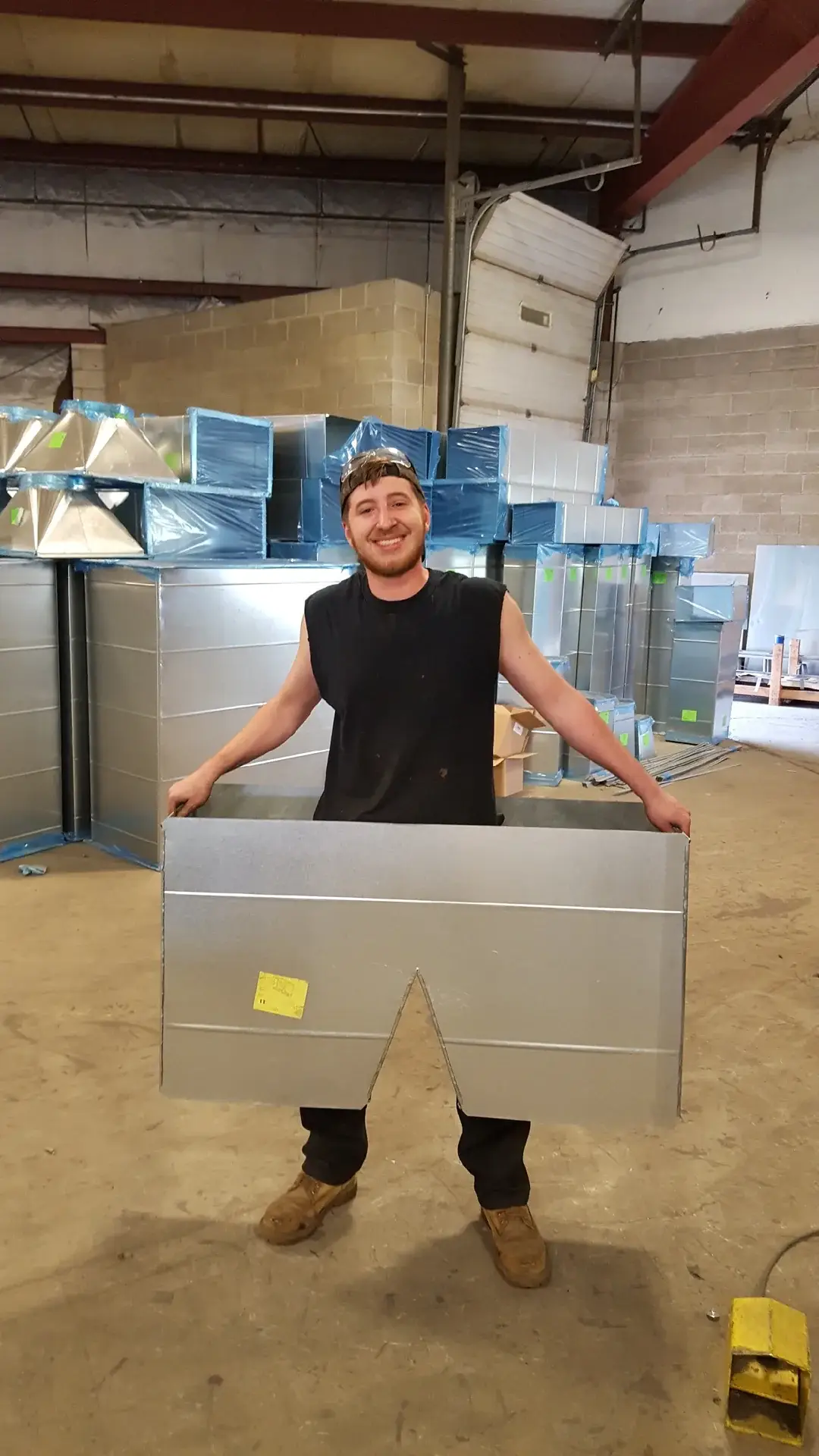 Danbury Winair team member holding a custom rectangular sheet metal fitting