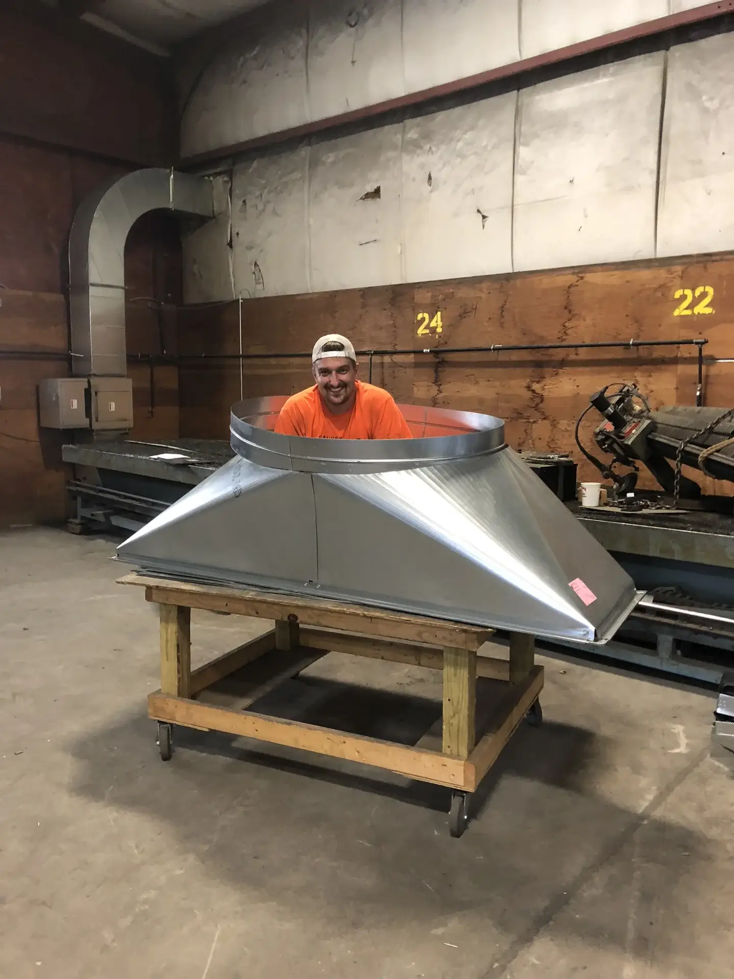 Team member with a large custom sheet metal transition in the Danbury Winair shop
