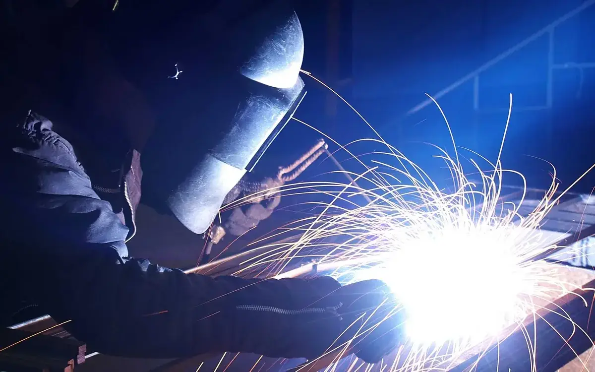 Welder working on metal with bright sparks